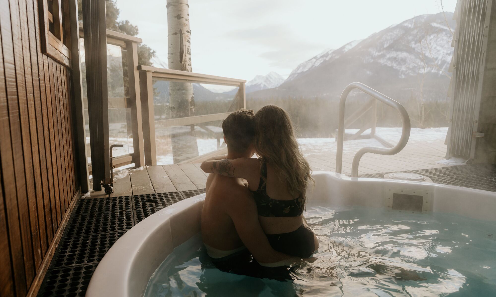 A couple in a hot tub in winter at the Juniper Hotel in Banff.