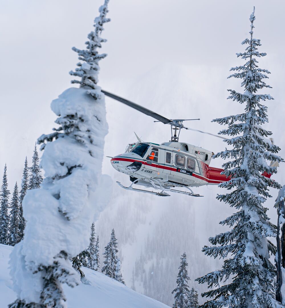A helicopter landing in the snow for a heli-skiing adventure with CMH