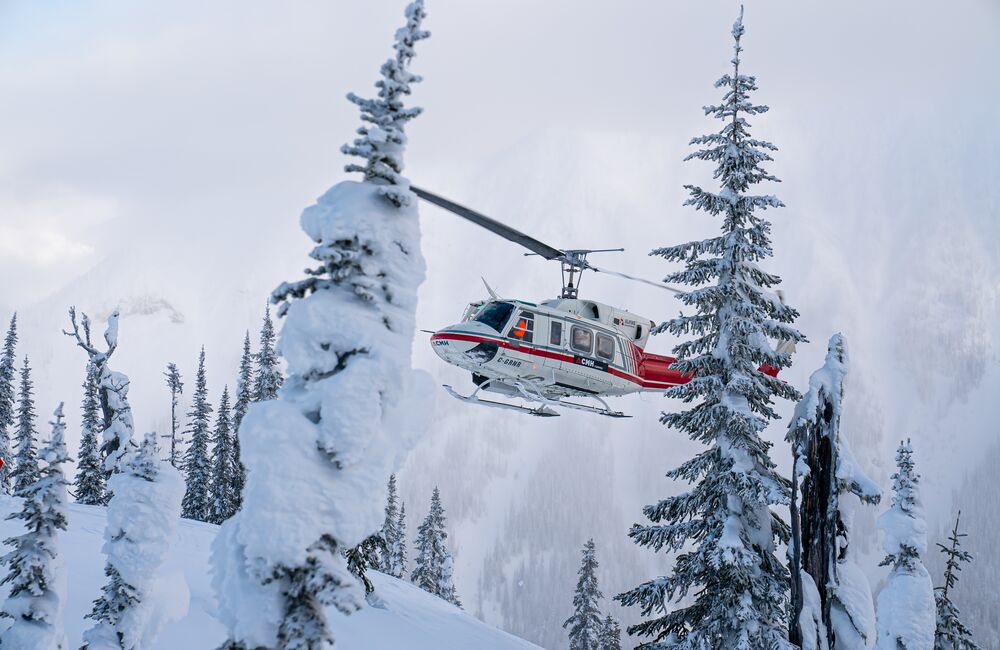 A helicopter landing in the snow for a heli-skiing adventure with CMH