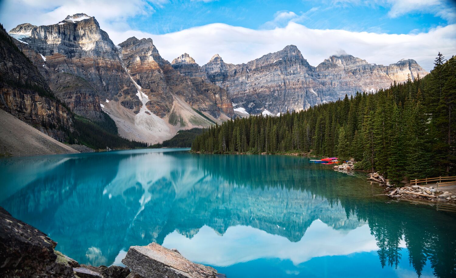 The turquoise waters of Moraine Lake reflecting mountain peaks on a blue bird day in Banff NAtional Park.