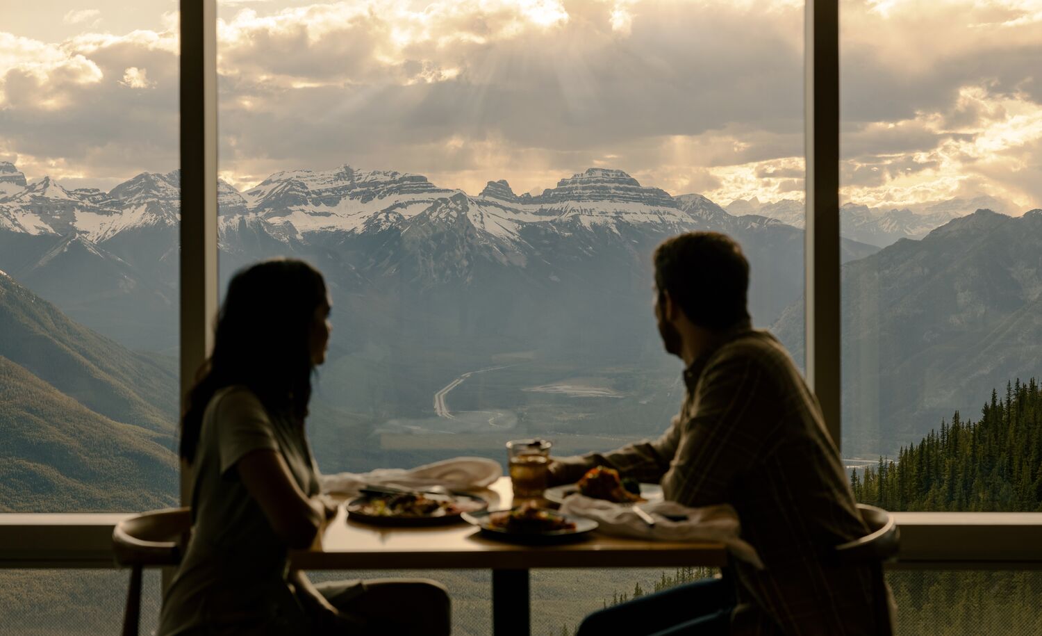 Two people eating looking at the views at Sky Bistro in Banff National Park.
