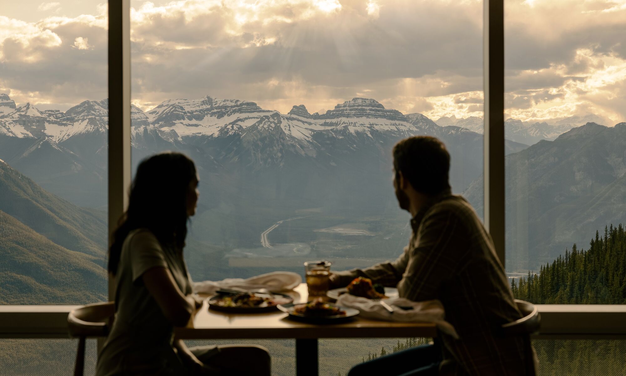 Two people eating looking at the views at Sky Bistro in Banff National Park.