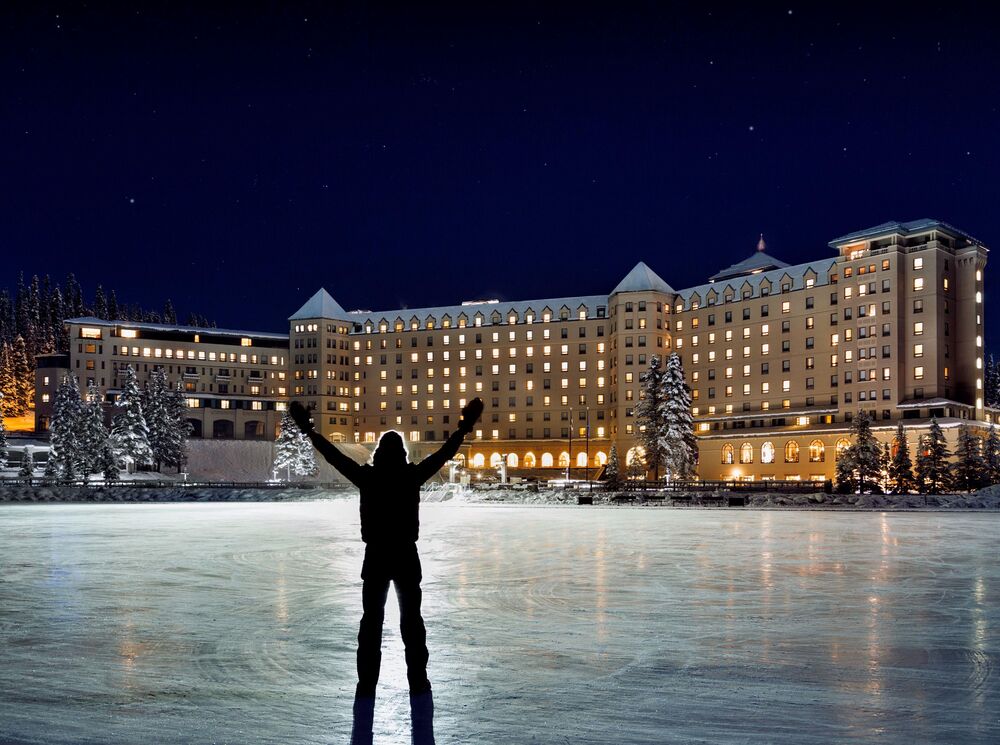 Photo of a man enjoying the view of the Fairmont Chateau Lake Louise in Banff National Park on a winter night.