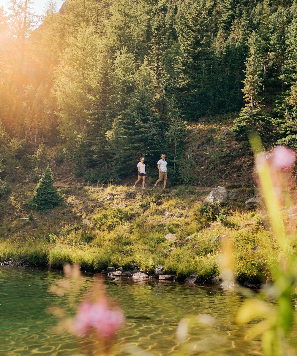 A couple hiking the shoreline of Lake Agnes in the Lake Louise area