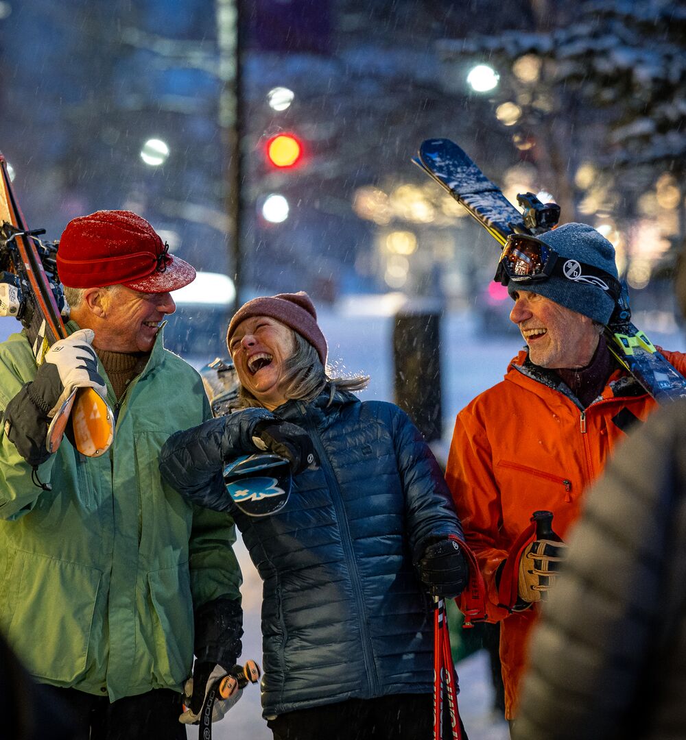 Friends carrying skis heading to après in downtown Banff.