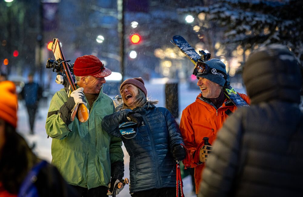 Friends carrying skis heading to après in downtown Banff.