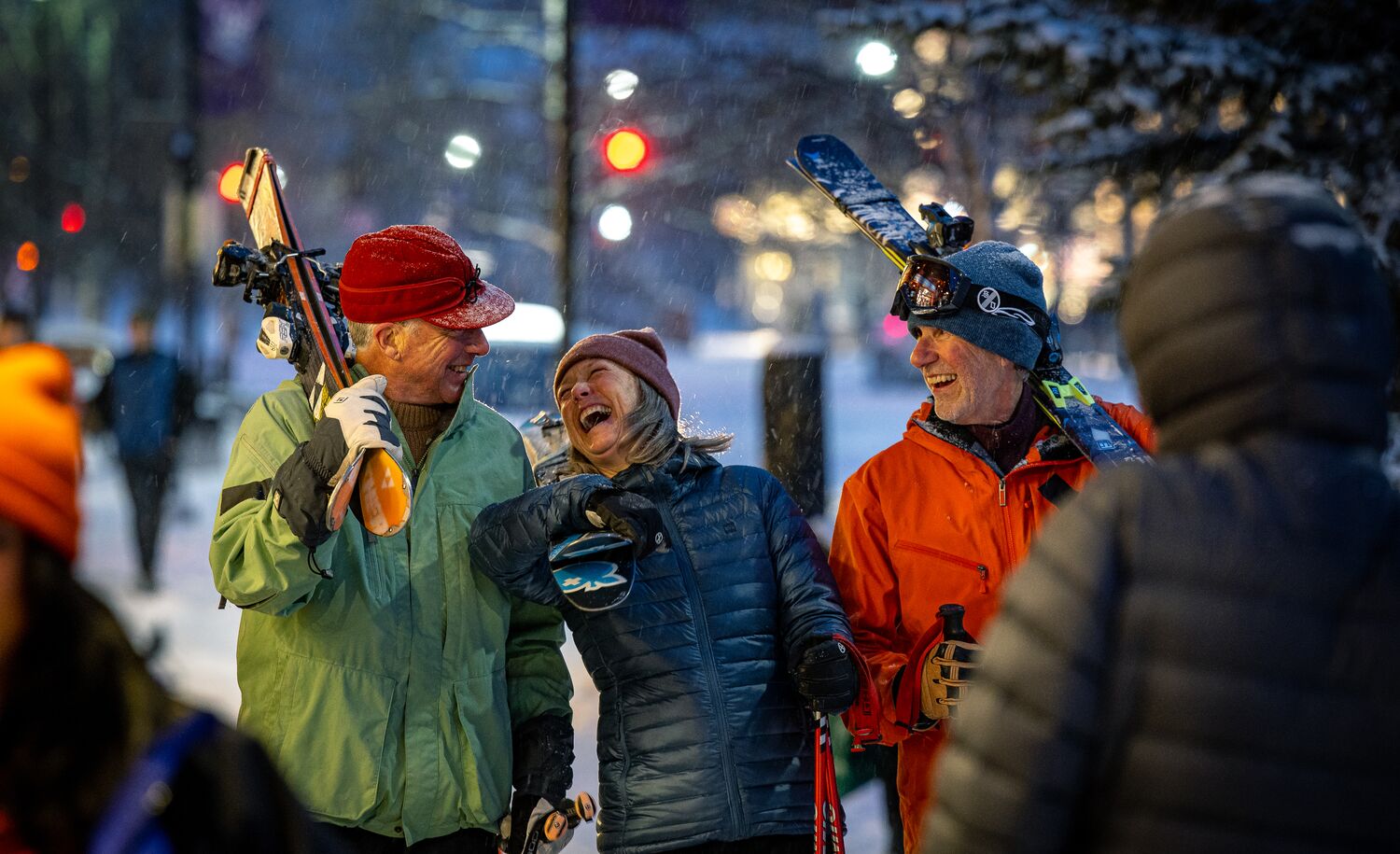 Three friends walk through the Banff Town with their skis on a snowy winter day in Banff National Park