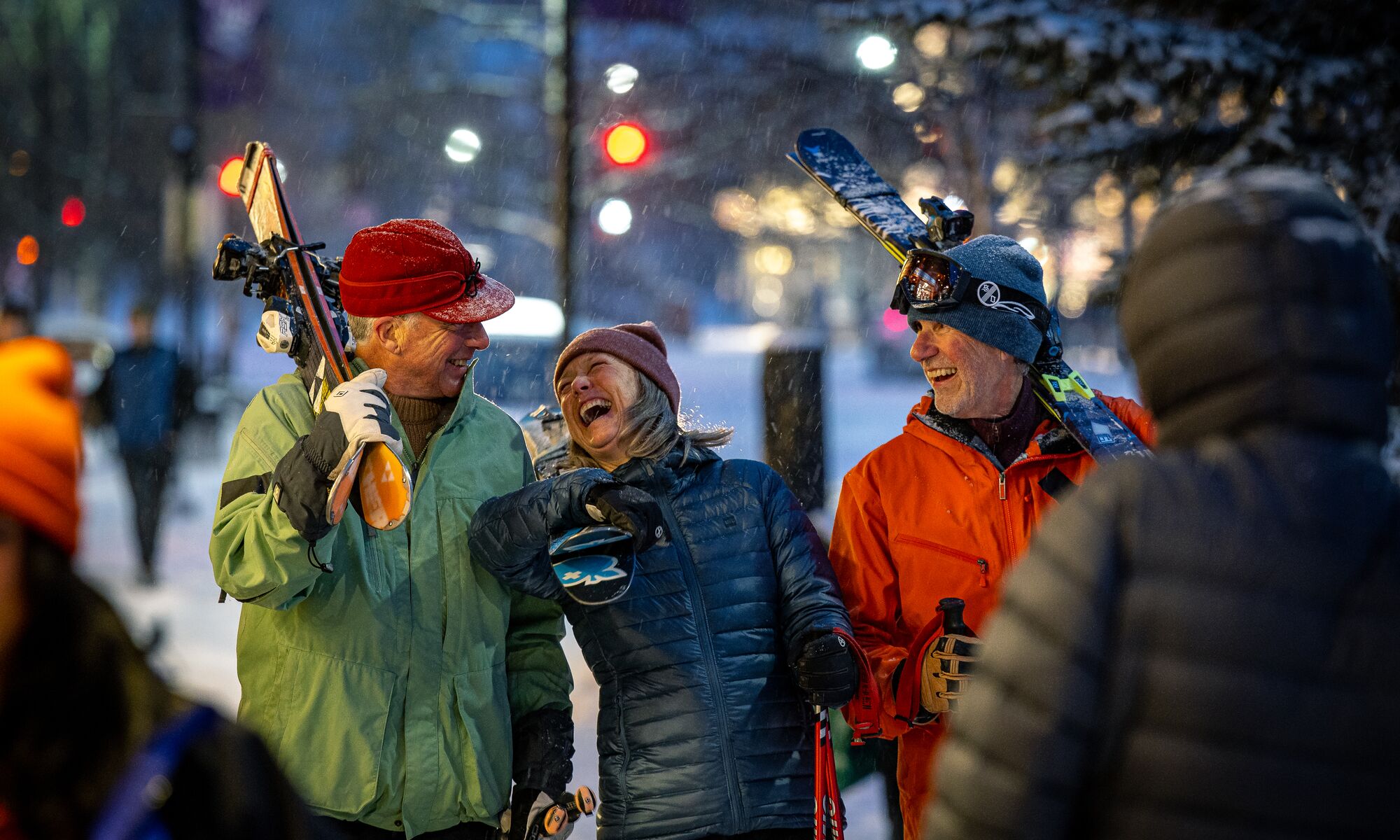 Three friends walk through the Banff Town with their skis on a snowy winter day in Banff National Park