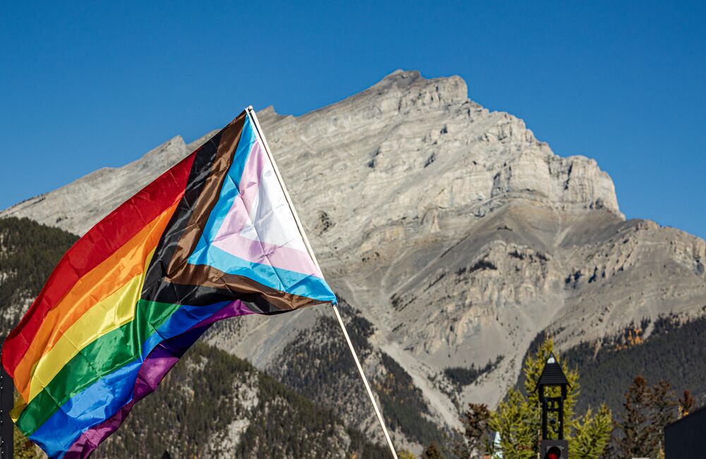 A pride flag waves in the air in front of Cascade Mountain on Banff Ave in Banff National Park.