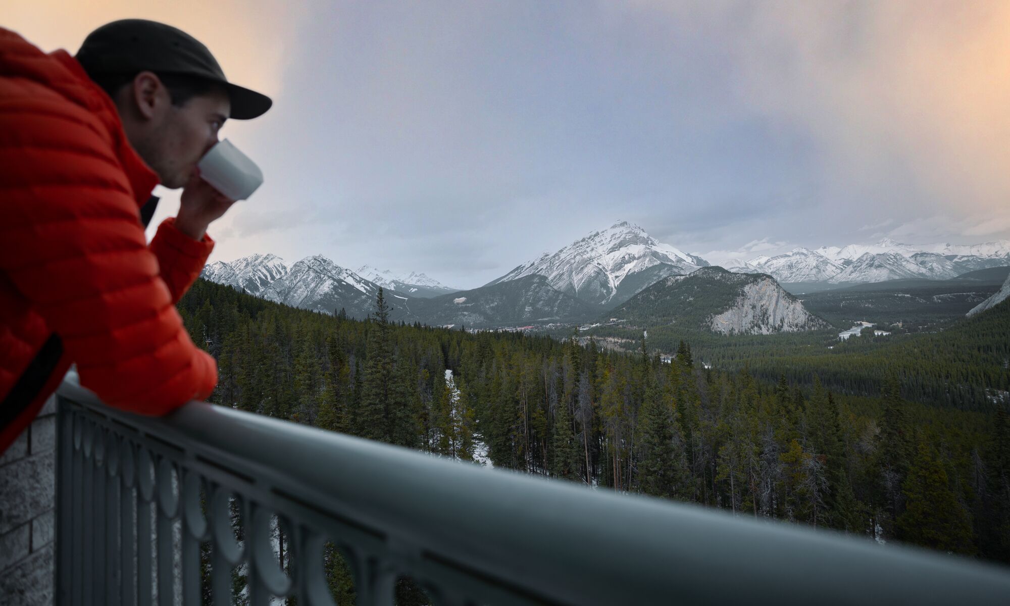 A person enjoys a coffee at the rimrock Resort Hotel in the early morning while looking at mountains.