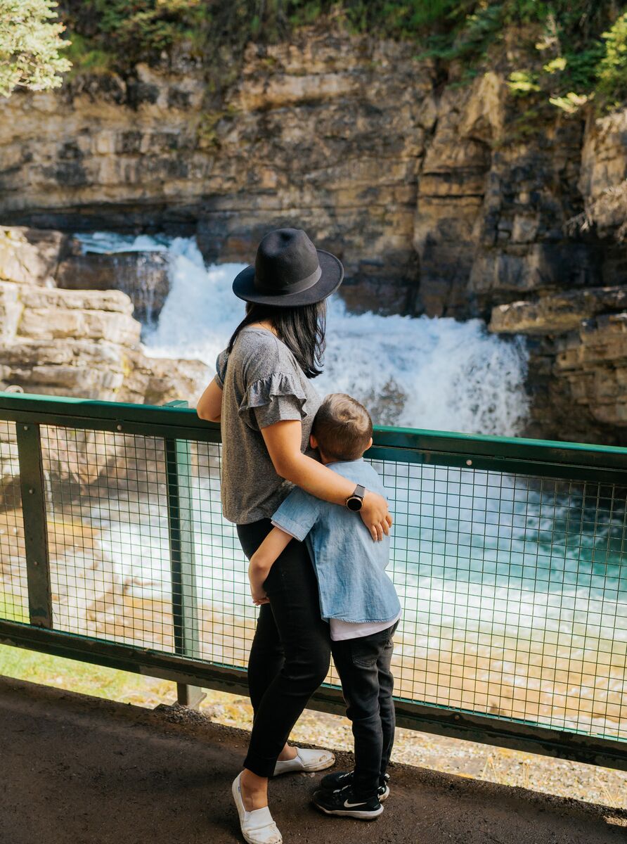 A mother and son look at the upper falls at Johnston Canyon in Banff National Park in the summer.