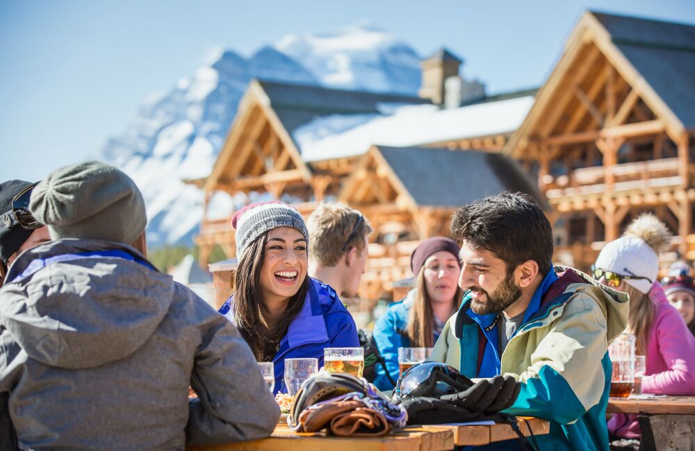 A group of friends enjoy the sun with some food and drinks after a day of skiing at Lake Louise. 