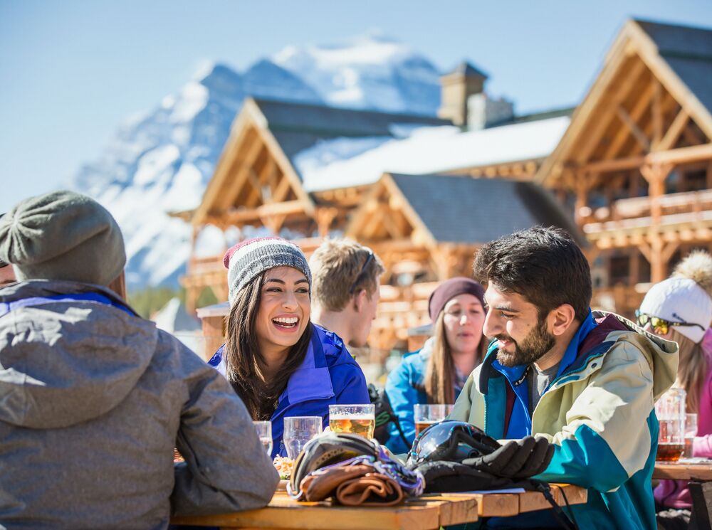 A group of friends enjoy the sun with some food and drinks after a day of skiing at Lake Louise. 