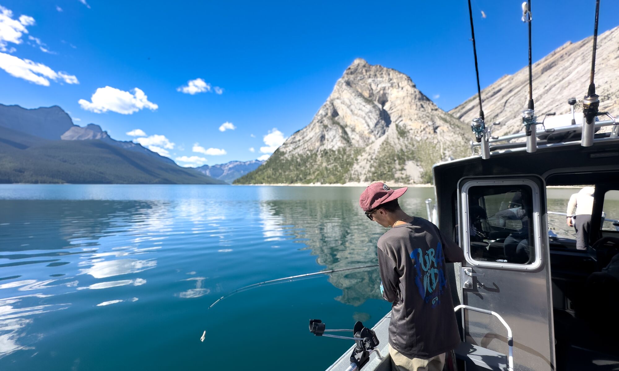 A person fishing on a boat in Lake Minnewanka, a popular thing to do in Banff in July