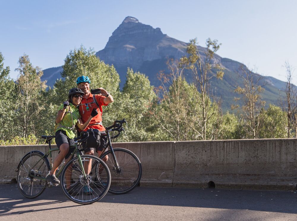 A couple stop on the side of the Bow Valley Parkway to take a selfie in front of Pilot Mountain.