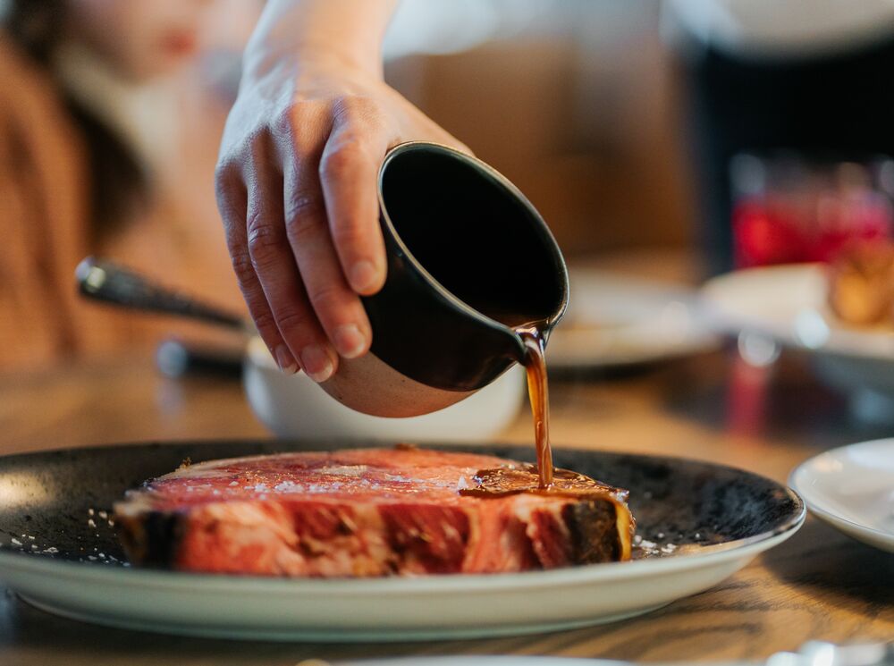 Au jus sauce is poured over a steak at a restaurant good for dietary restrictions in Banff, Canada.