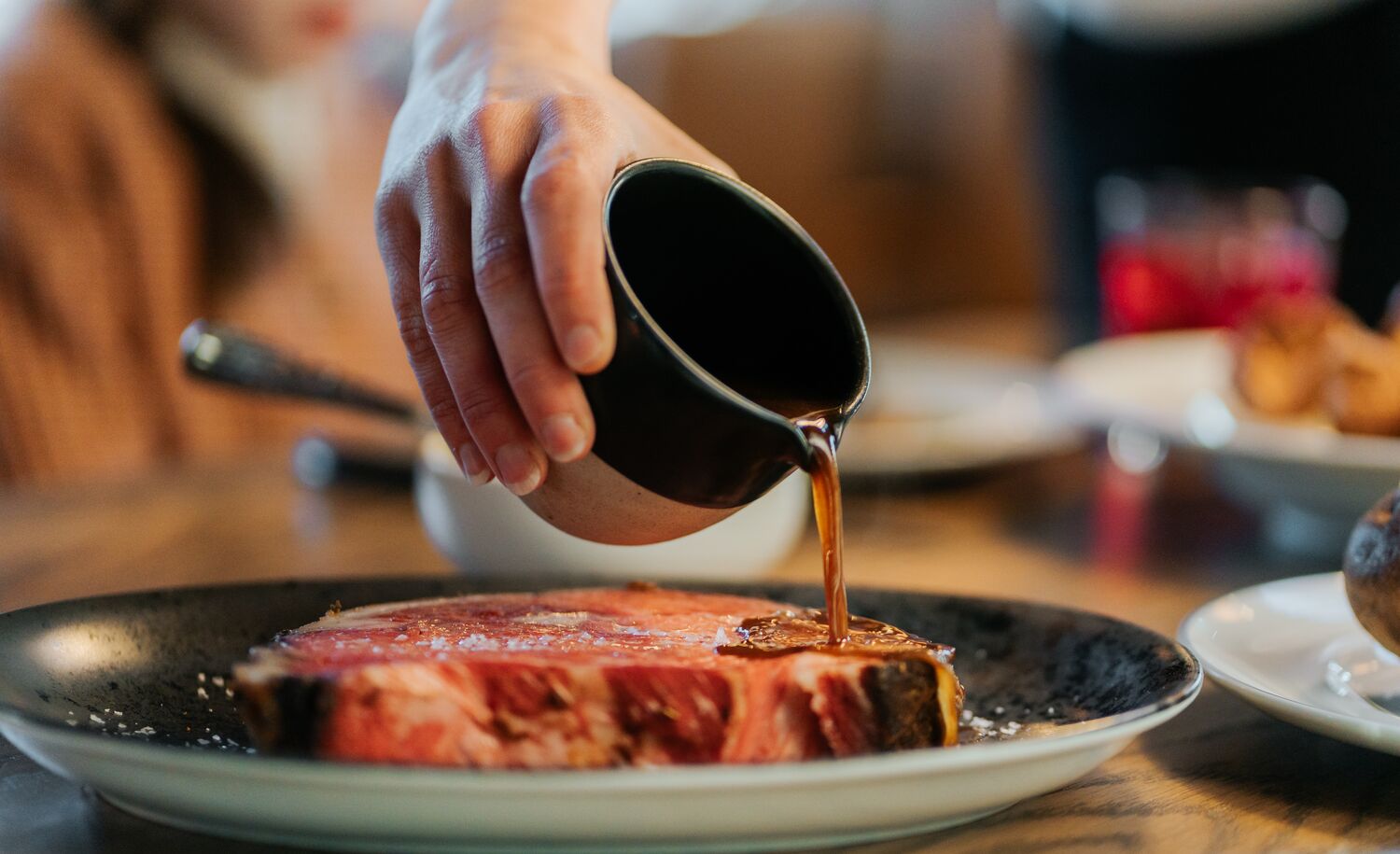 Au jus sauce is poured over a steak at a restaurant good for dietary restrictions in Banff, Canada.