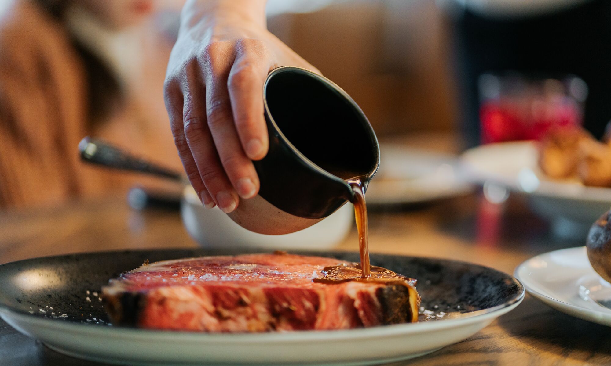 Au jus sauce is poured over a steak at a restaurant good for dietary restrictions in Banff, Canada.