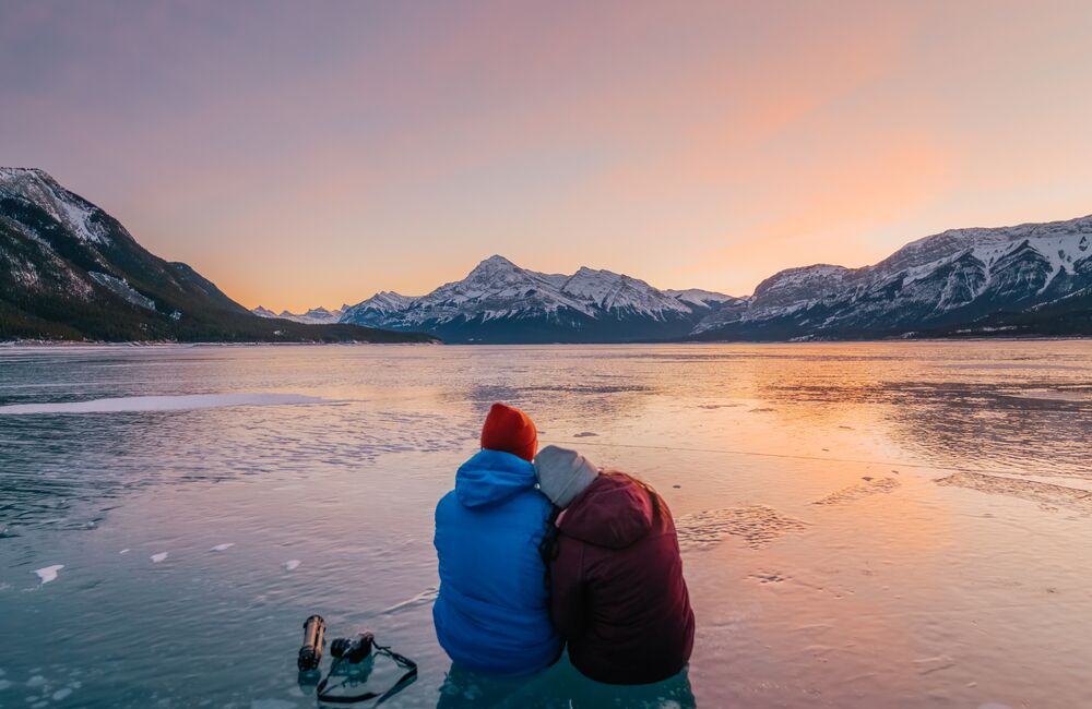 Two People sitting on the frozen ice bubbles of Abraham Lake near the Icefields Parkway