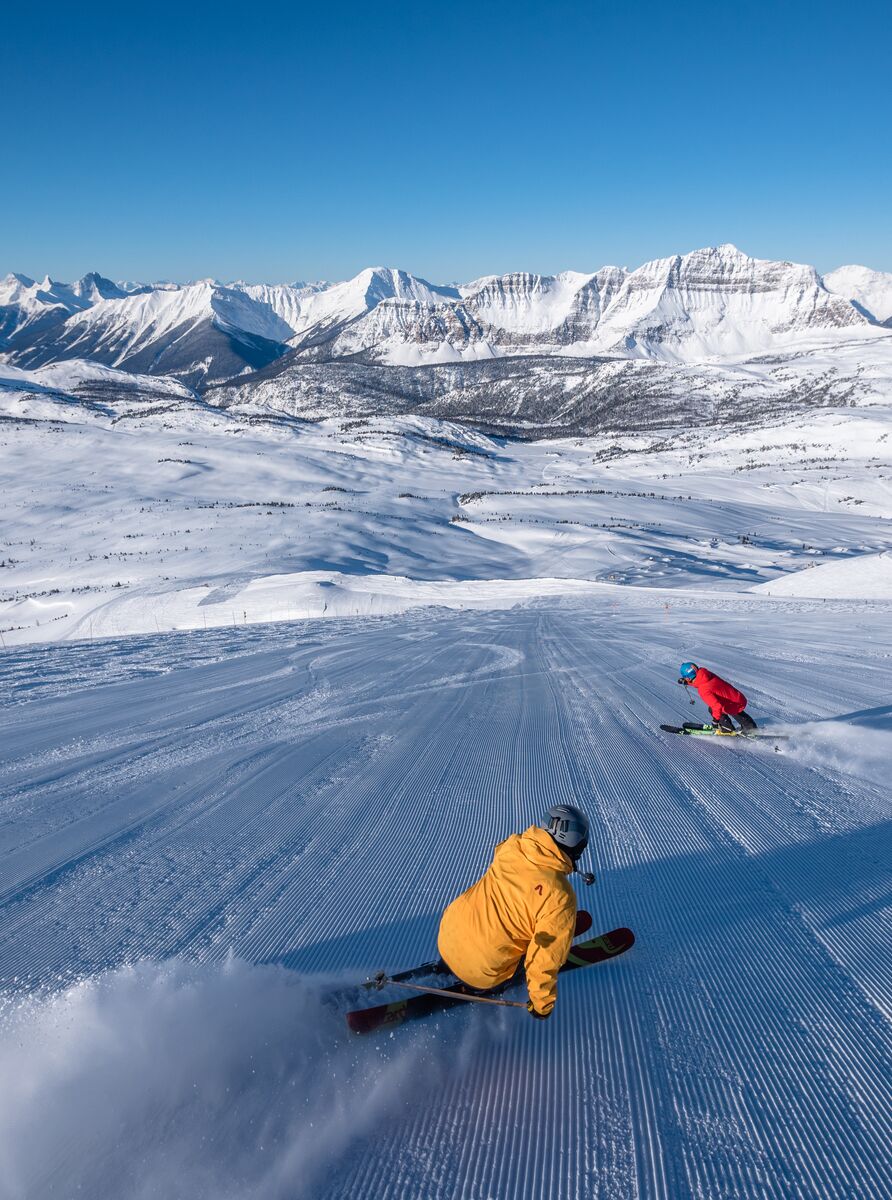Two people skiing a run at Sunshine Village on a bluebird day