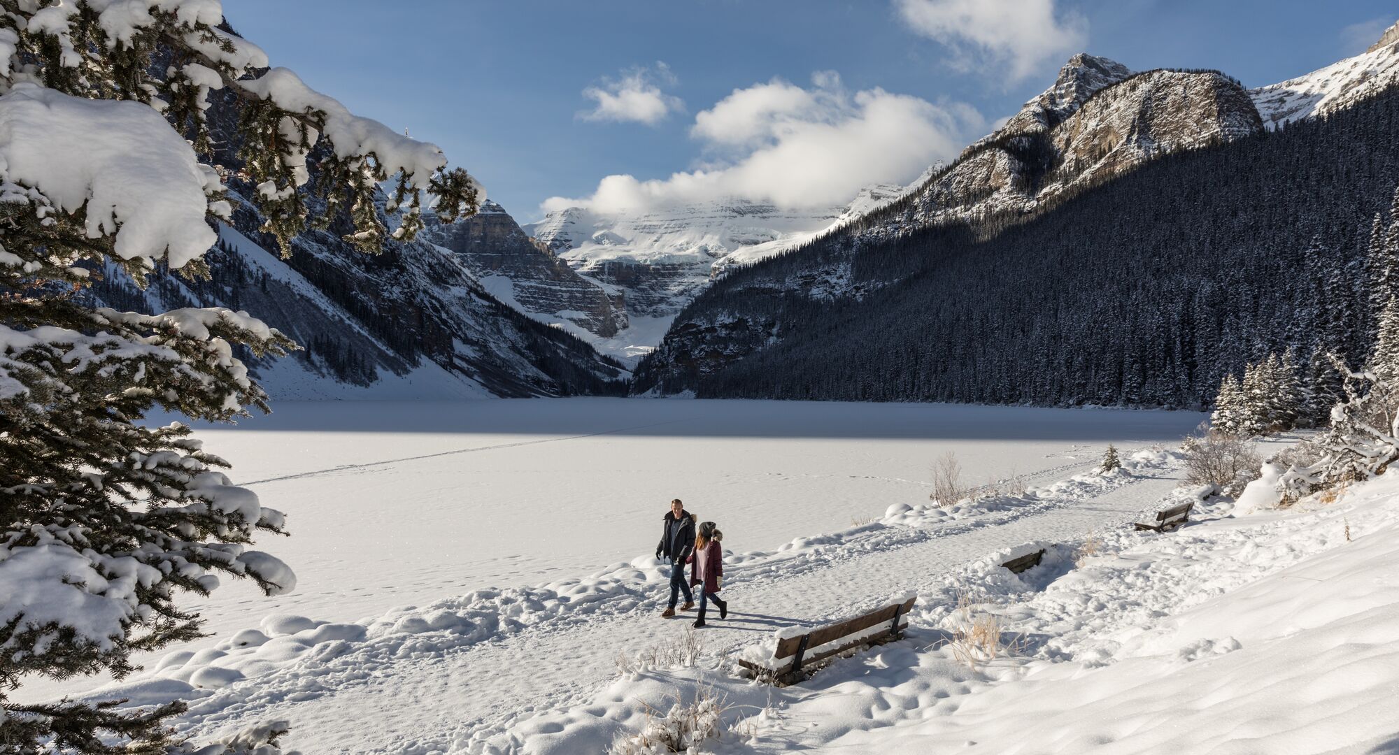Couple hiking the Lake Louise lakeshore trail in the winter in Banff National Park