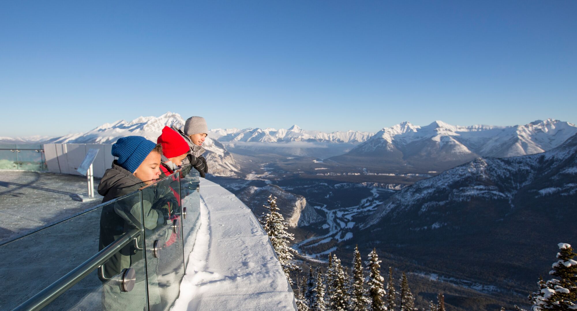 Three kids taking in the views of the mountains from the viewing deck at the top of the Banff Gondola