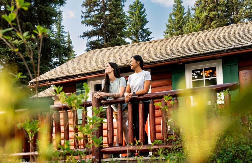 Two people looking out from the balcony of a cabin in Banff National Park