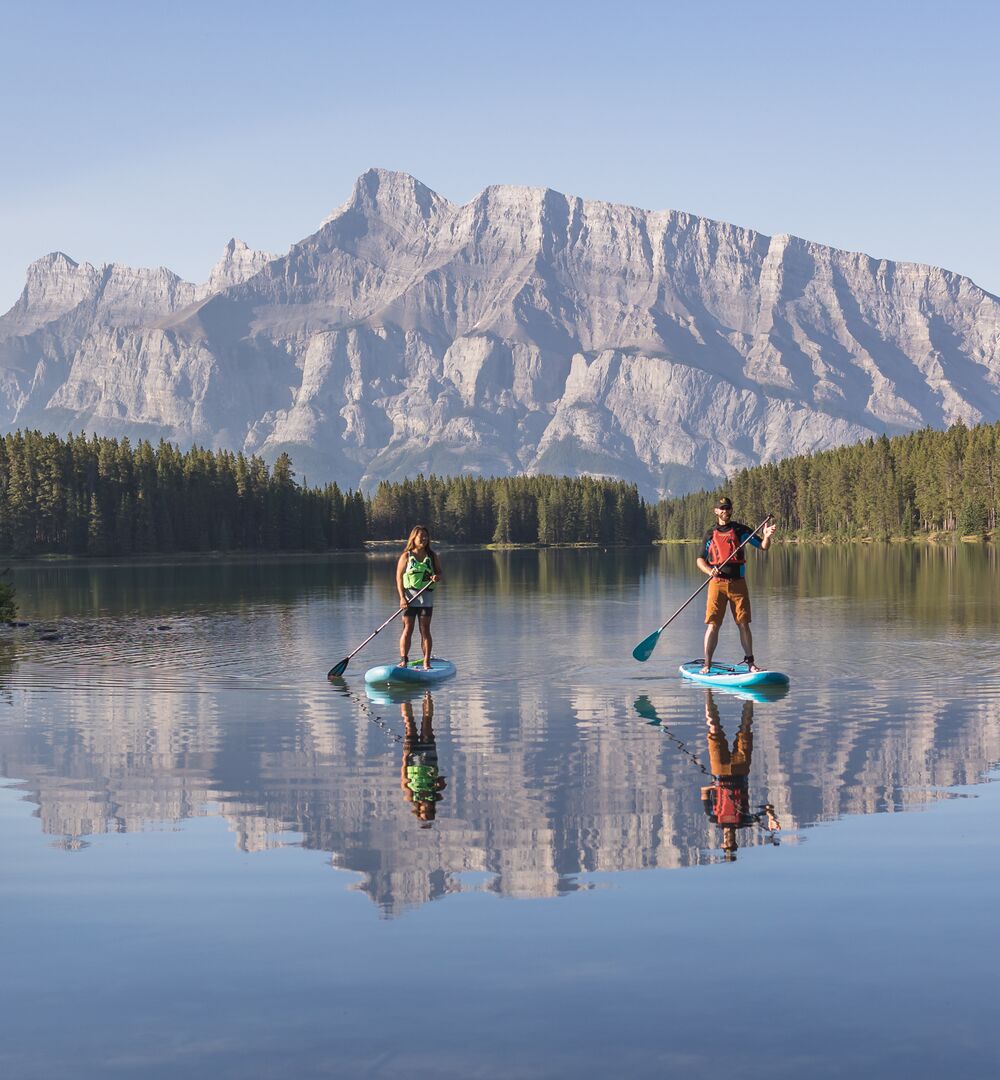 Two people stand up paddleboarding on Two Jack Lake in Banff National Park