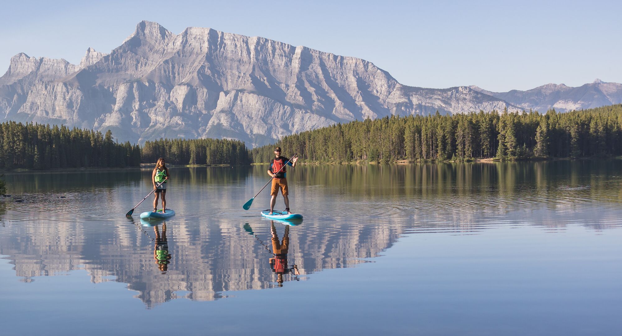 Two people stand up paddleboarding on Two Jack Lake in Banff National Park