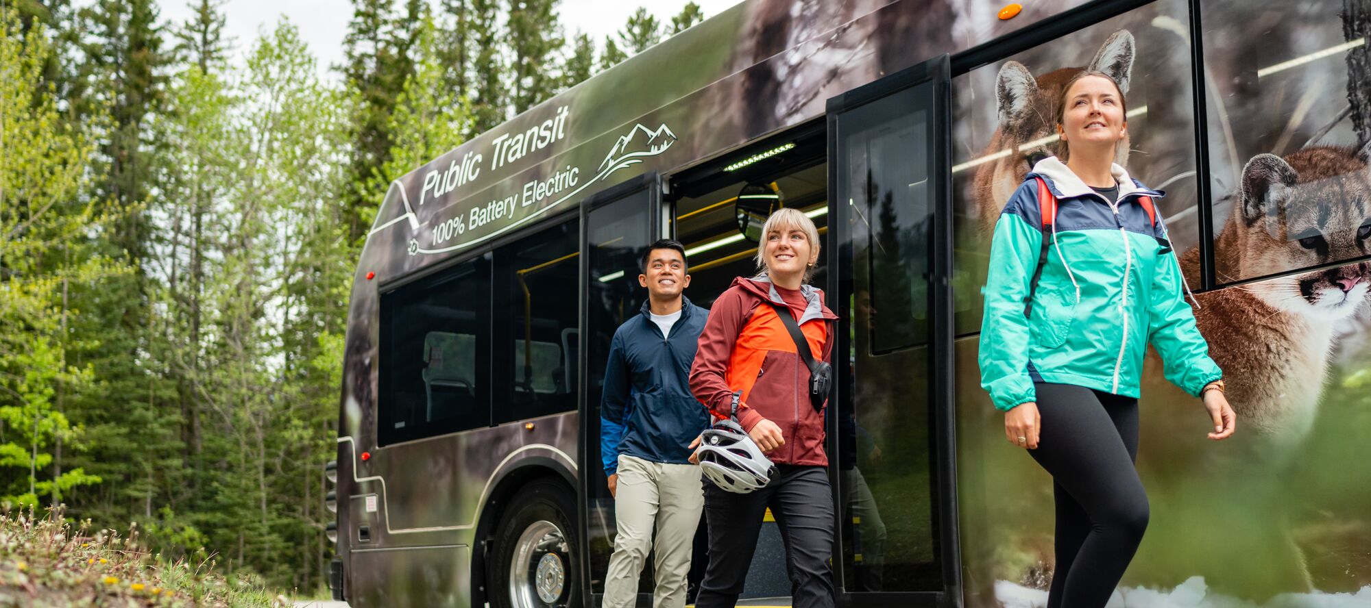 Three passengers disembark from a Roam Transit bus on the Minnewanka Loop