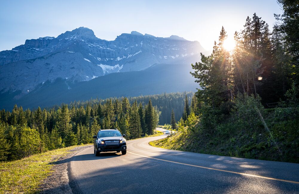 Car driving the Minnewanka Loop at sunset with Cascade Mountain in the background