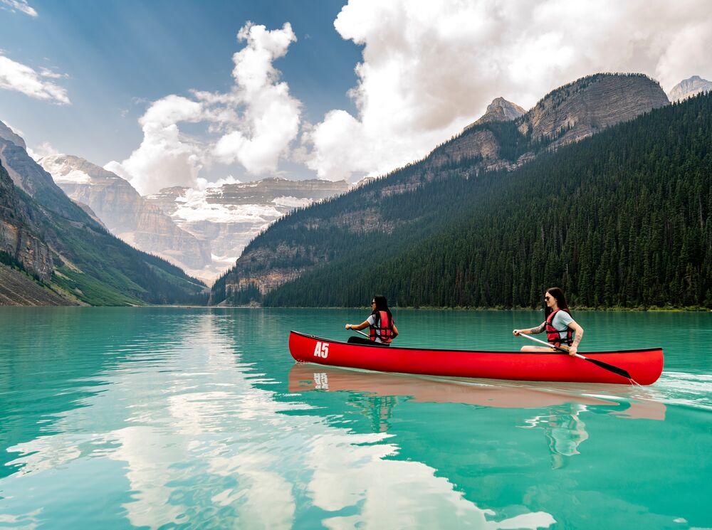 Two girls canoeing in a red canoe on Lake Louise in Banff National Park