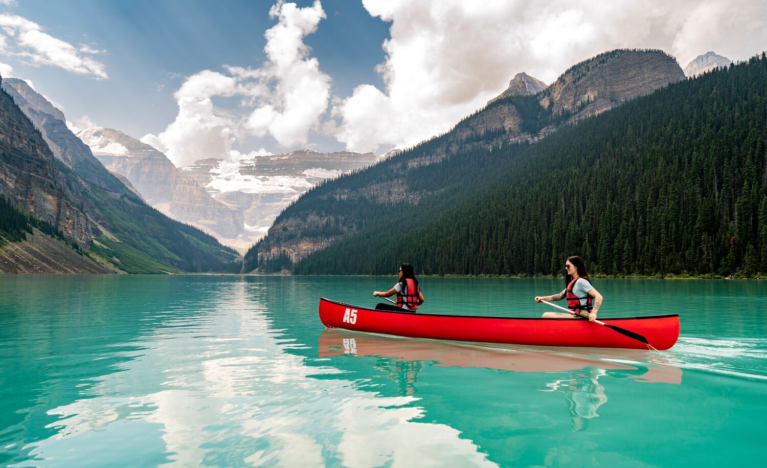 Two girls canoeing in a red canoe on Lake Louise in Banff National Park