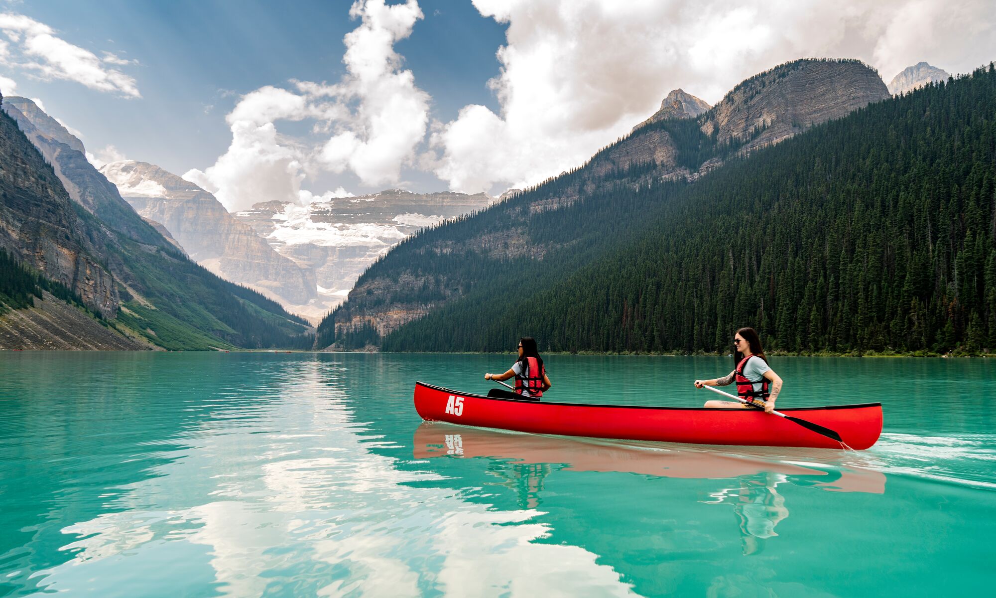 Two girls canoeing in a red canoe on Lake Louise in Banff National Park