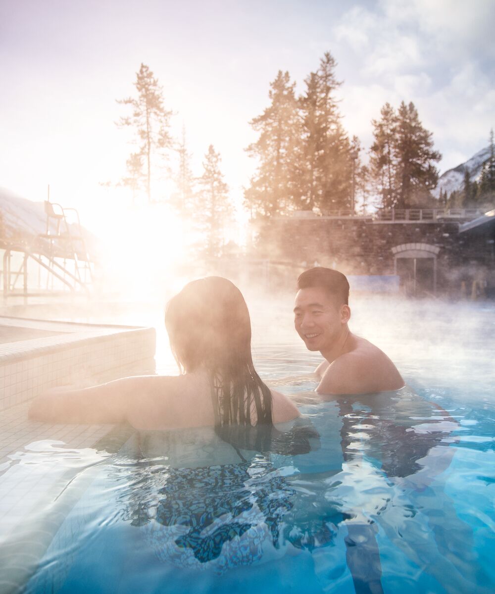 Two people enjoying a soak in the Banff Upper Hot Springs on a cool morning