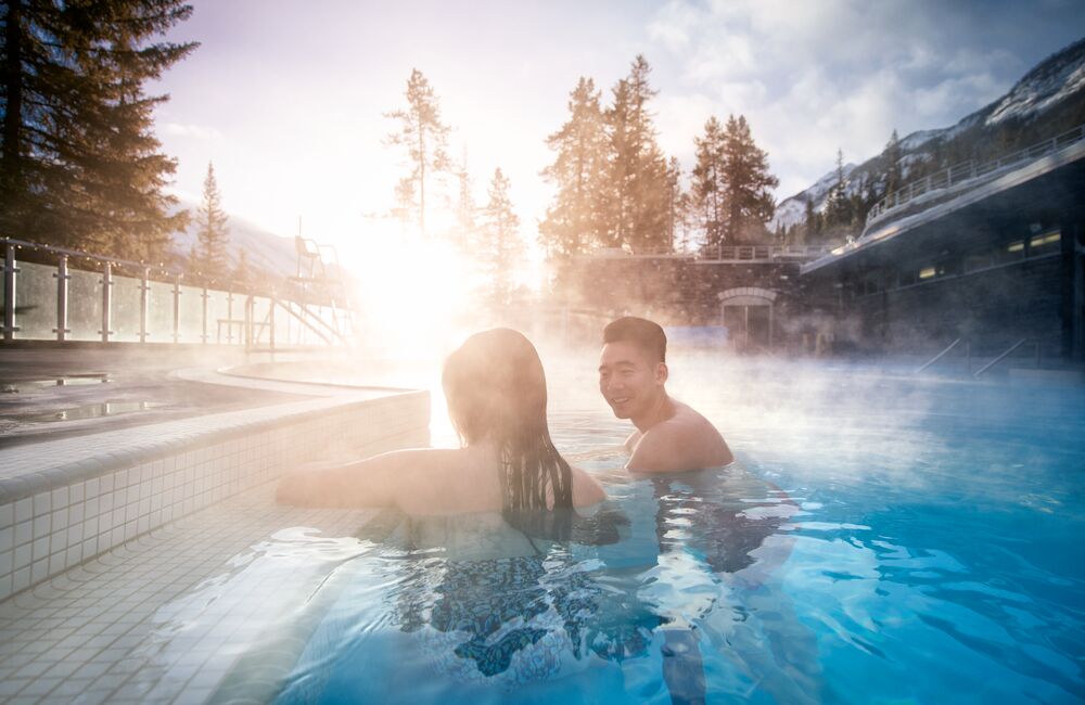 Two people enjoying a soak in the Banff Upper Hot Springs on a cool morning