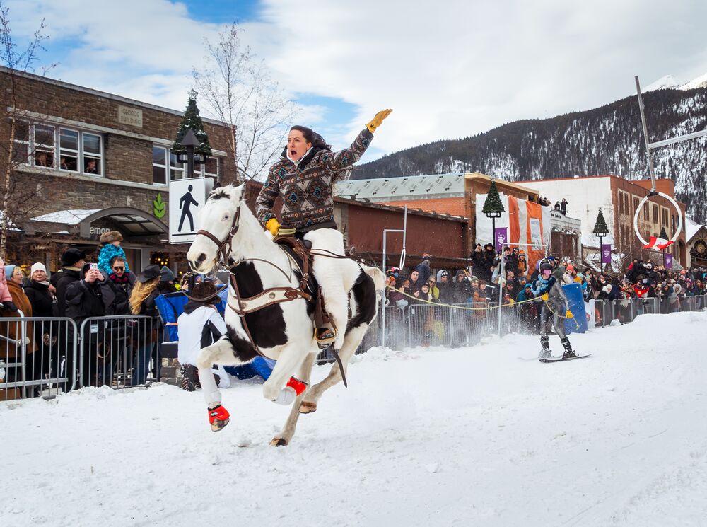 A horse and rider pull a skier down Banff Avenue during Skijoring in Banff.