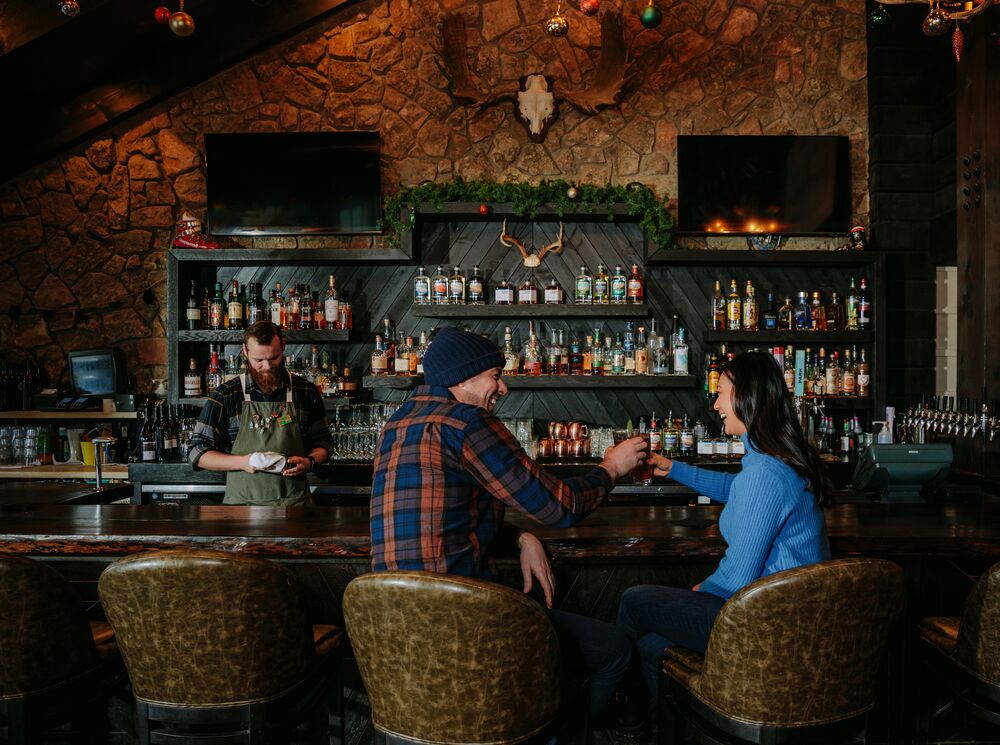 Two people sit at the bar at Park Distillery in Banff National Park.