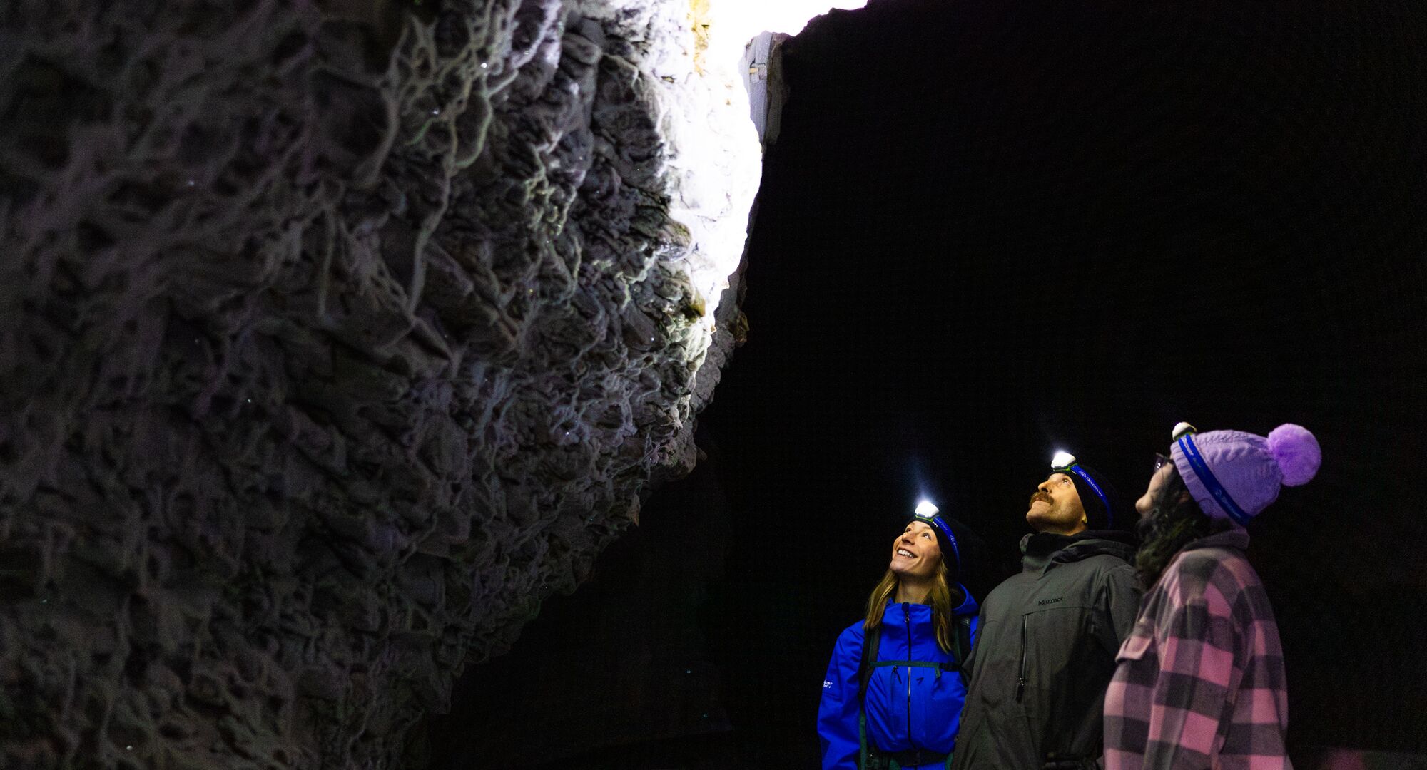 Three people with headlamps on, on a guided night hike through Johnston Cayon in the winter.