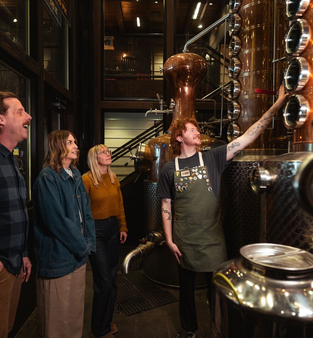 Three people take part in the PARK Distillery on-site tour with a guide in Banff National Park.
