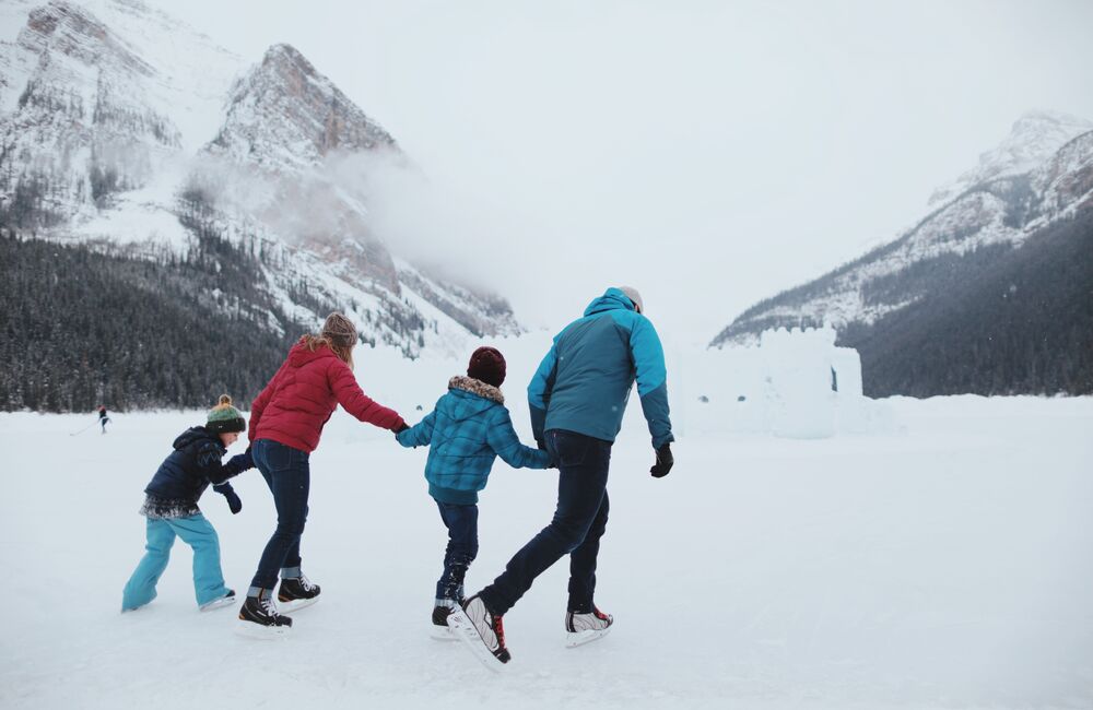 A family of four skate on frozen Lake Louise with an ice castle behind them in Banff National Park.
