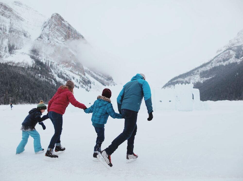 A family of four skate on frozen Lake Louise with an ice castle behind them in Banff National Park.
