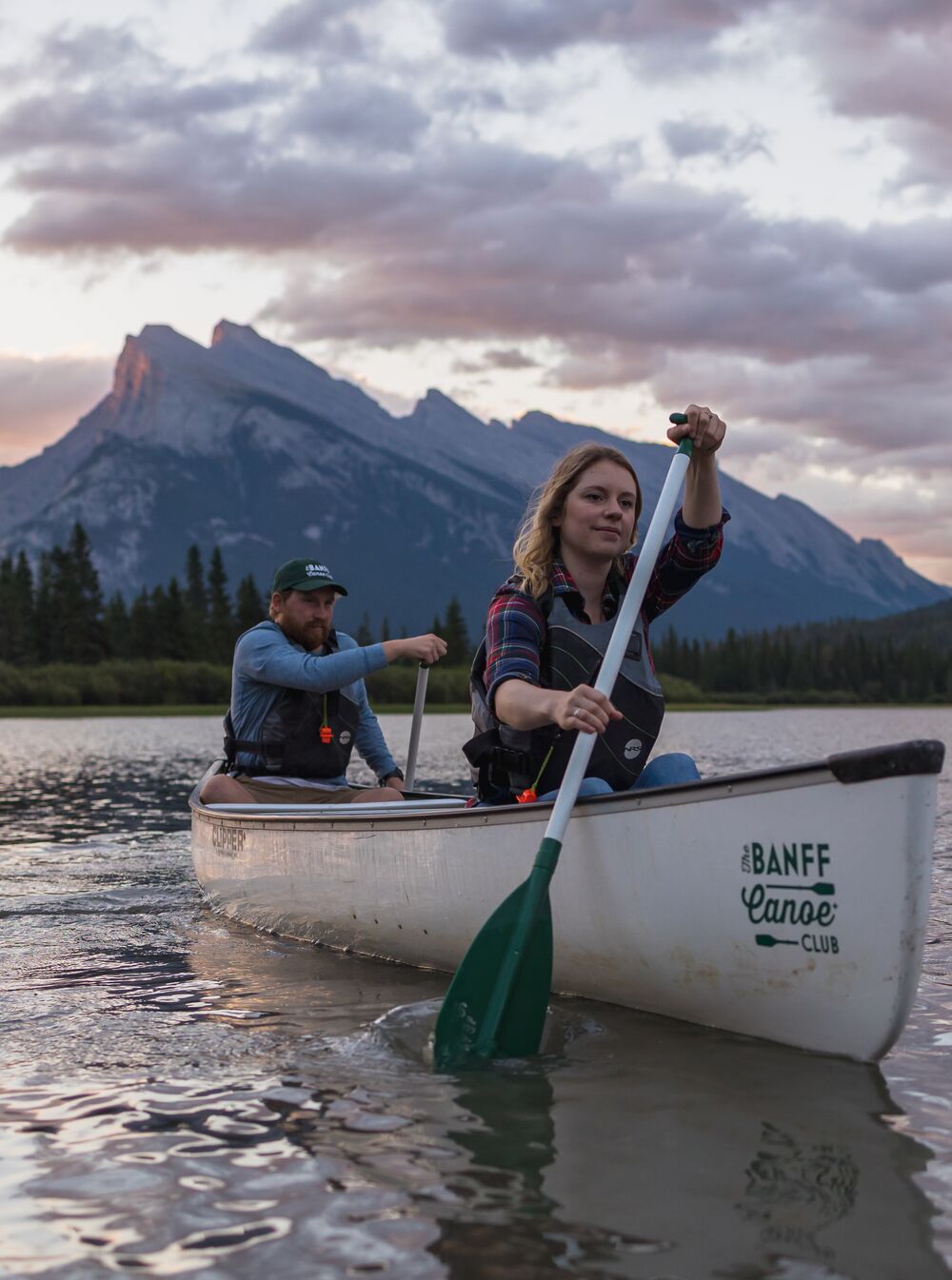Two people paddling in a canoe on the turquoise waters of Bow Lake in Banff National Park