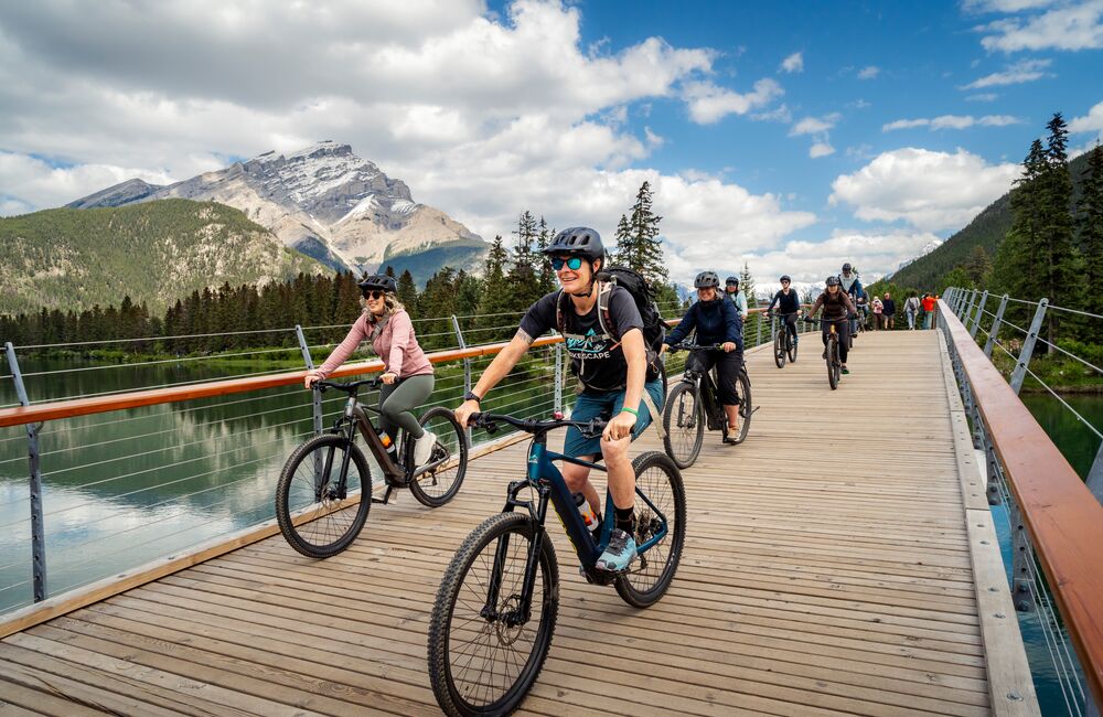 Group of people e-biking across the Banff Pedestrian Bridge