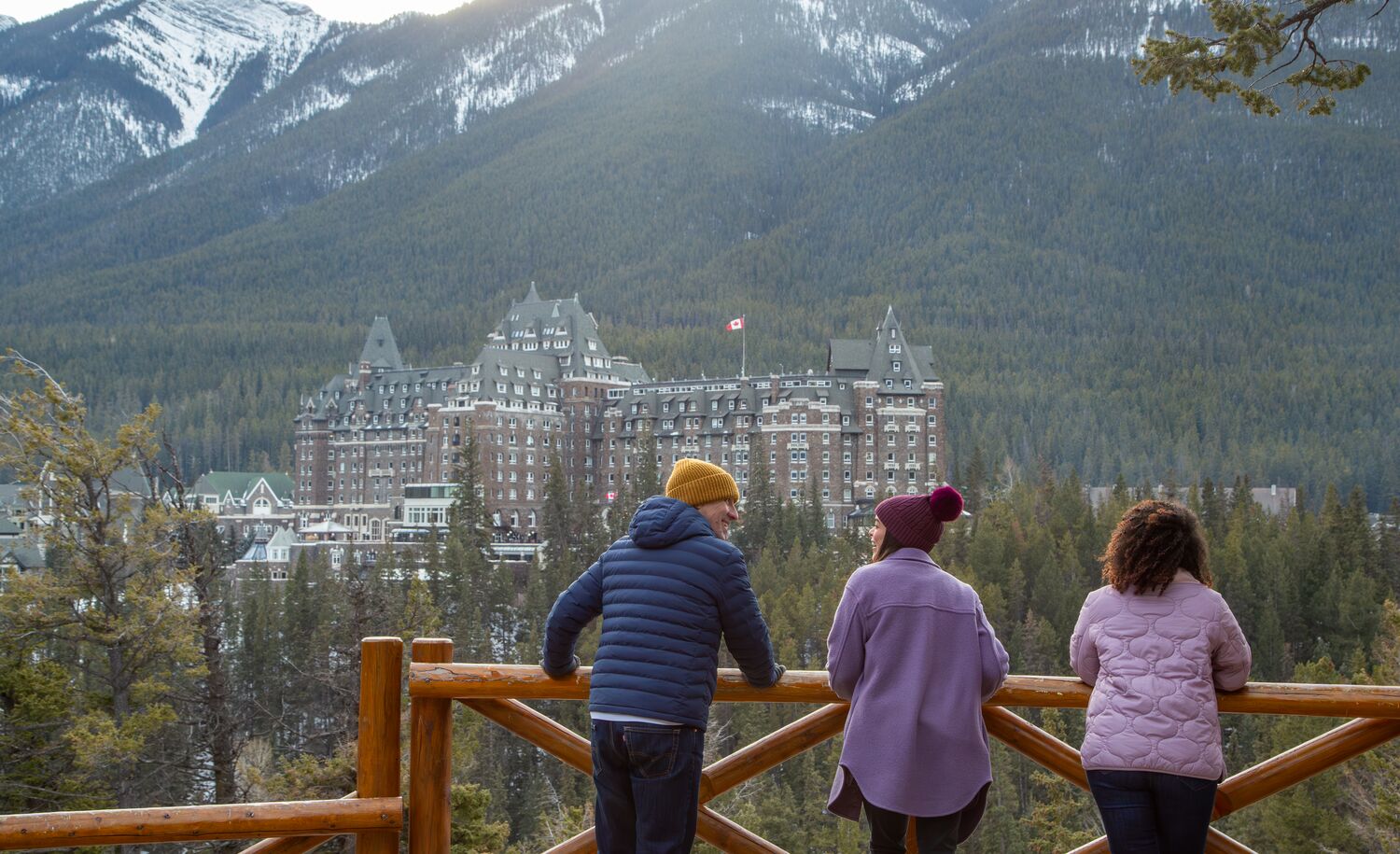 Three people at Surprise Corner viewpoint looking at the Fairmont Banff Springs in Banff National Park