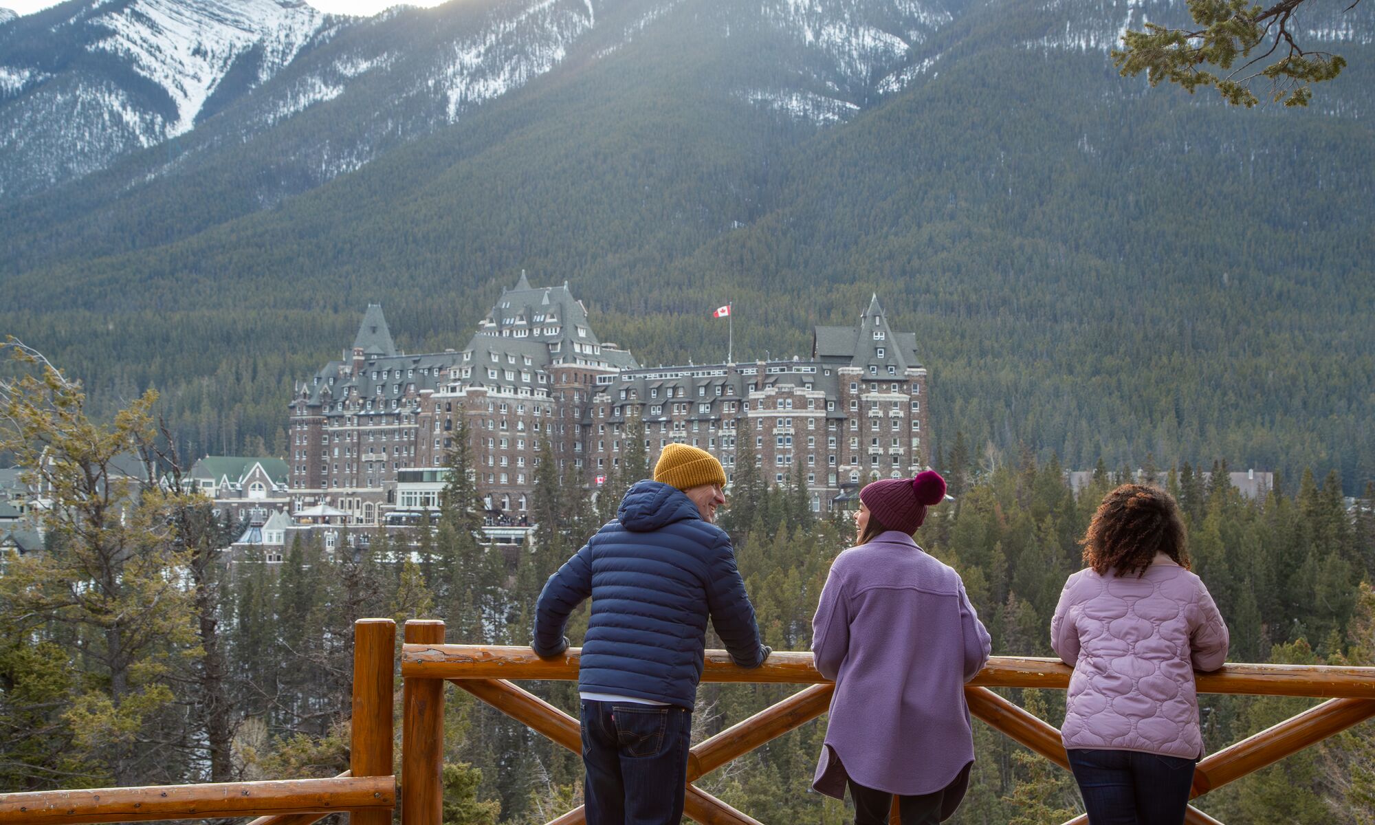 Three people at Surprise Corner viewpoint looking at the Fairmont Banff Springs in Banff National Park