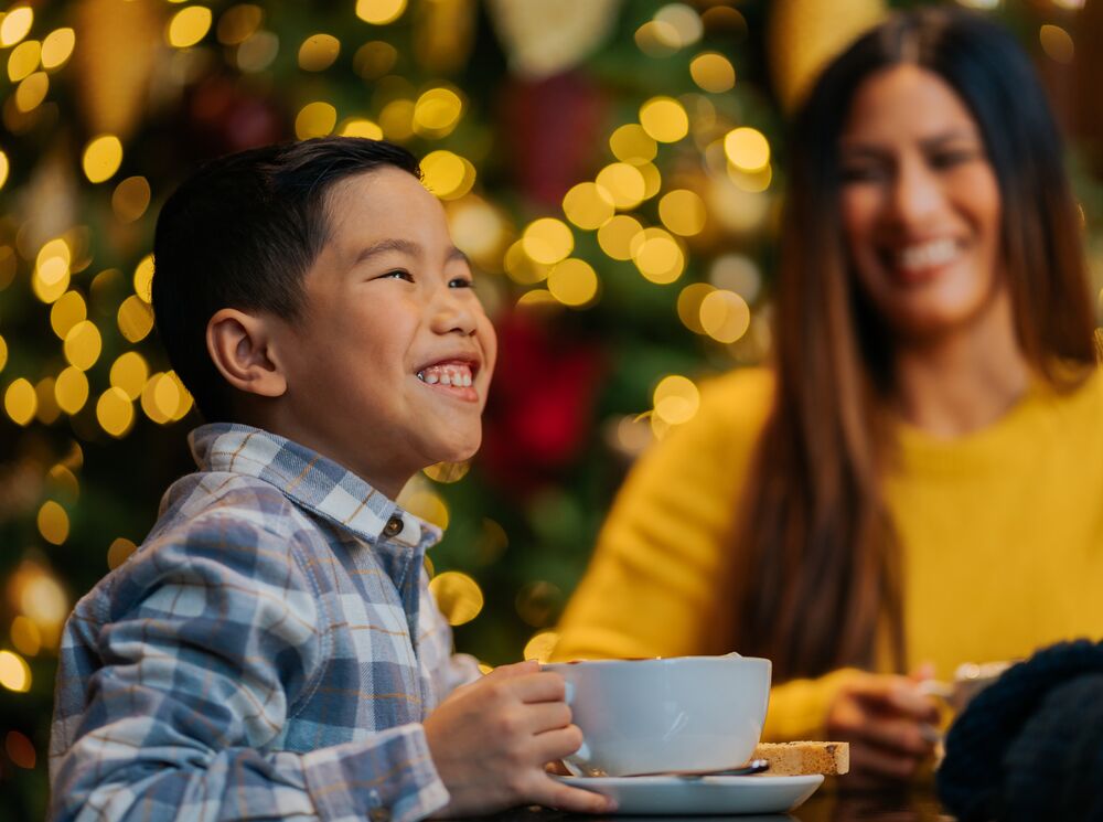 A young boy enjoys a big hot chocolate drink in the Rimrock Hotel in Banff National Park at Christmas.