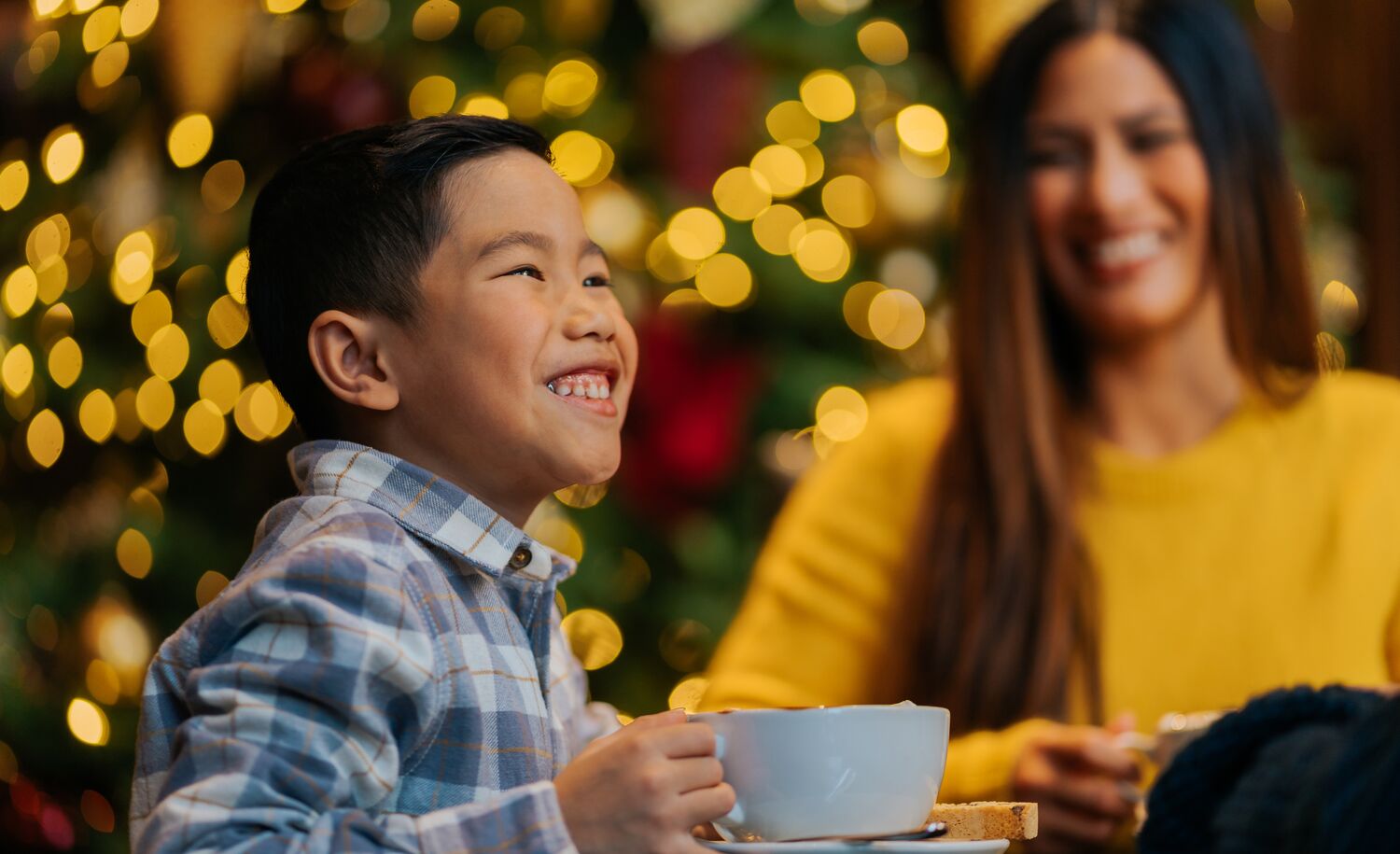 A young boy enjoys a big hot chocolate drink in the Rimrock Hotel in Banff National Park at Christmas.