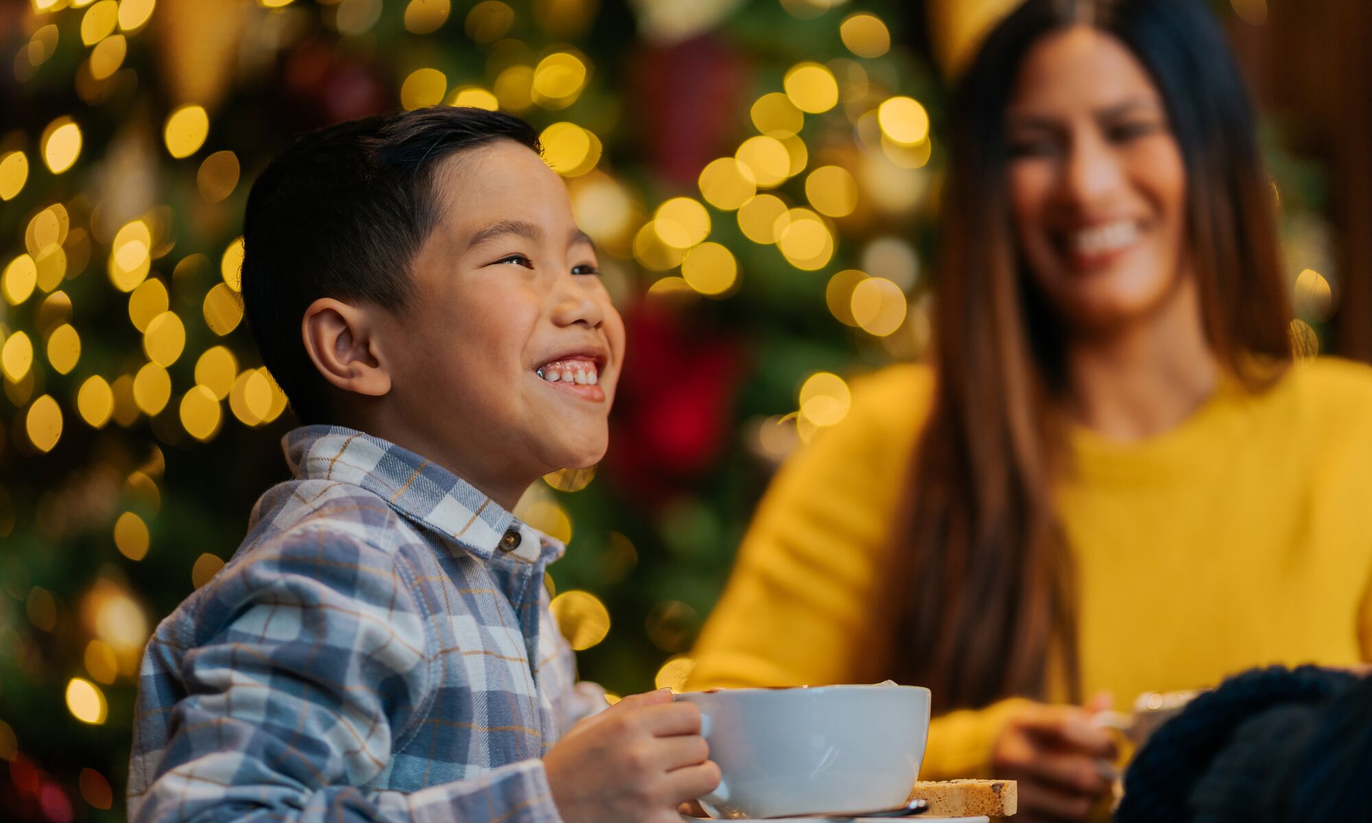 A young boy enjoys a big hot chocolate drink in the Rimrock Hotel in Banff National Park at Christmas.