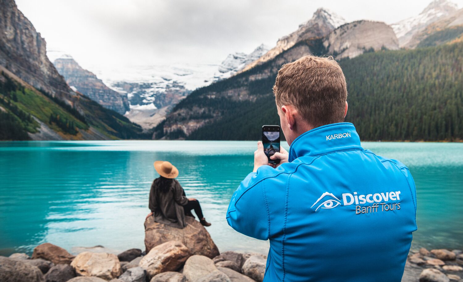 A Discover Banff Tours guide takes a photo of a person at Lake Louise in Banff National Park.